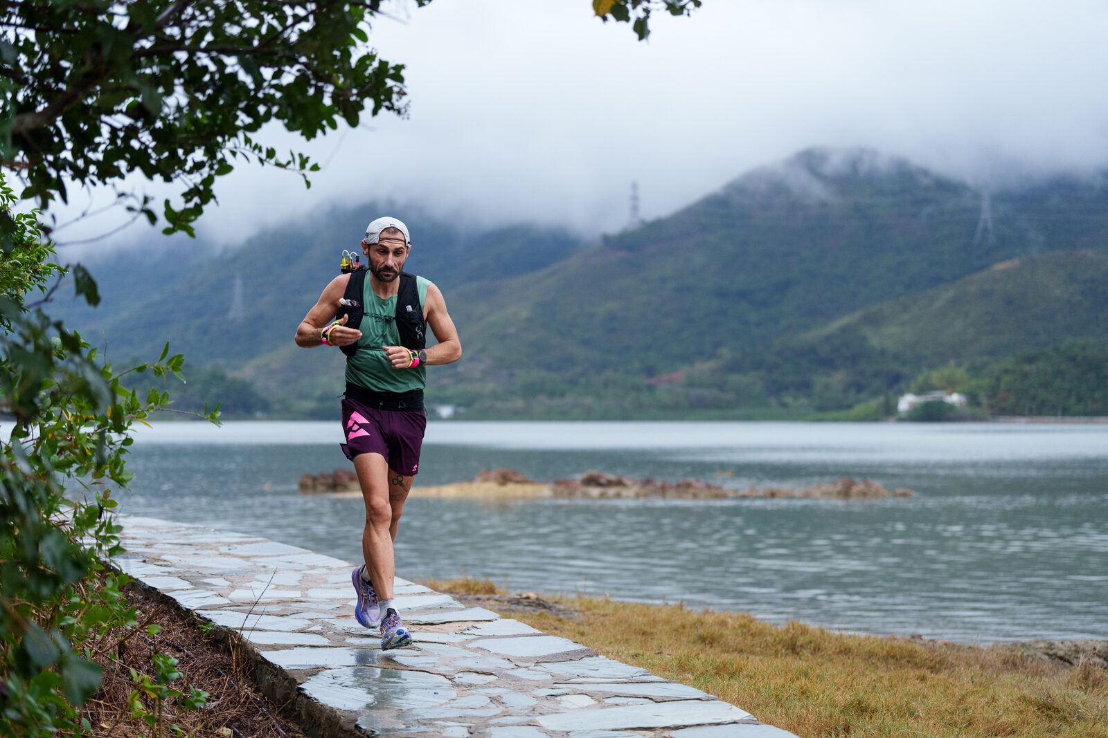 Runner on a lakeside path beneath misty mountains