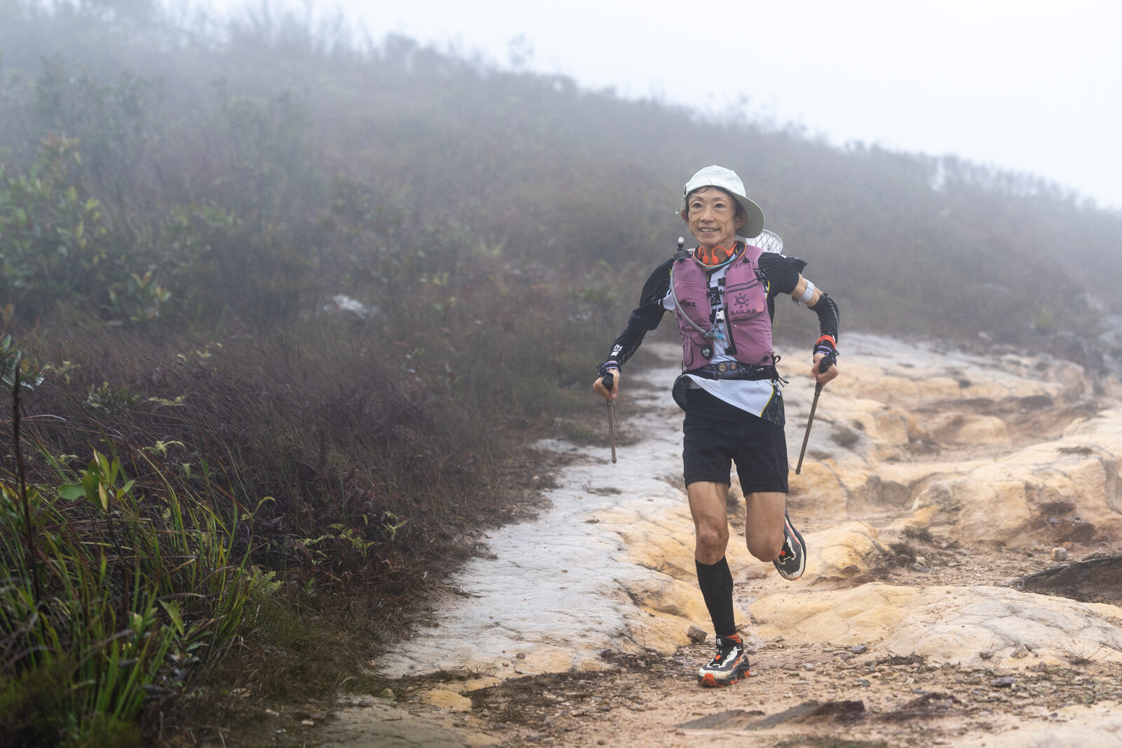 Woman runner pushing up a wet, misty trail in the New Territories
