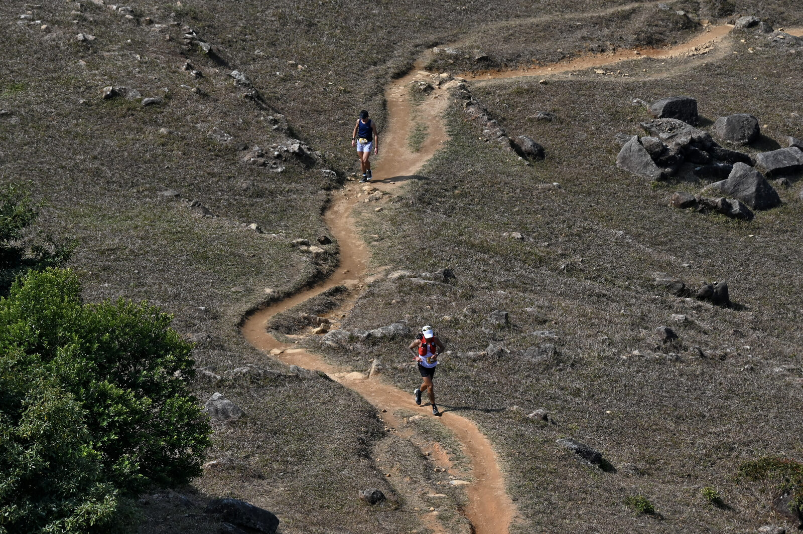 A lone runner on a winding trail carved through the mountains